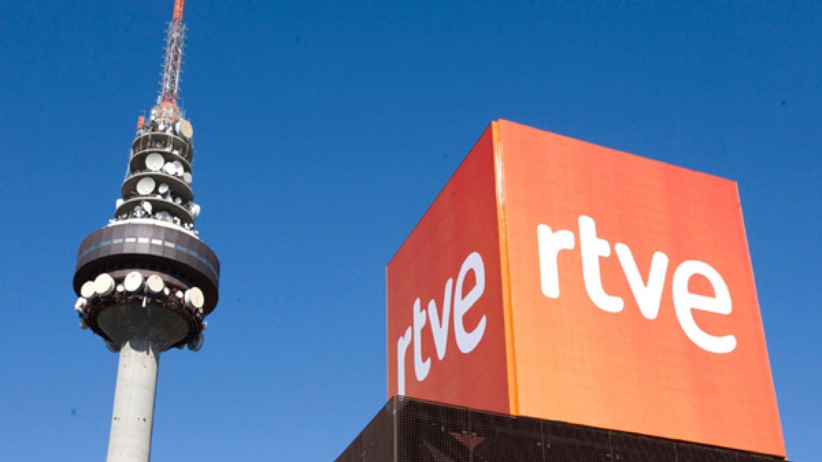 Torre "El Pirulí" y estructura cúbica naranja con logo "rtve" bajo cielo azul.