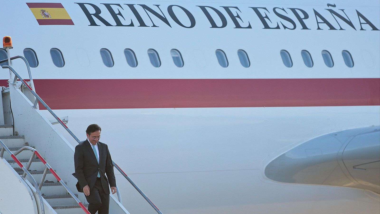 Pedro Sánchez desciende de un avión oficial del Reino de España. El avión es blanco con una franja roja y la bandera española visible.