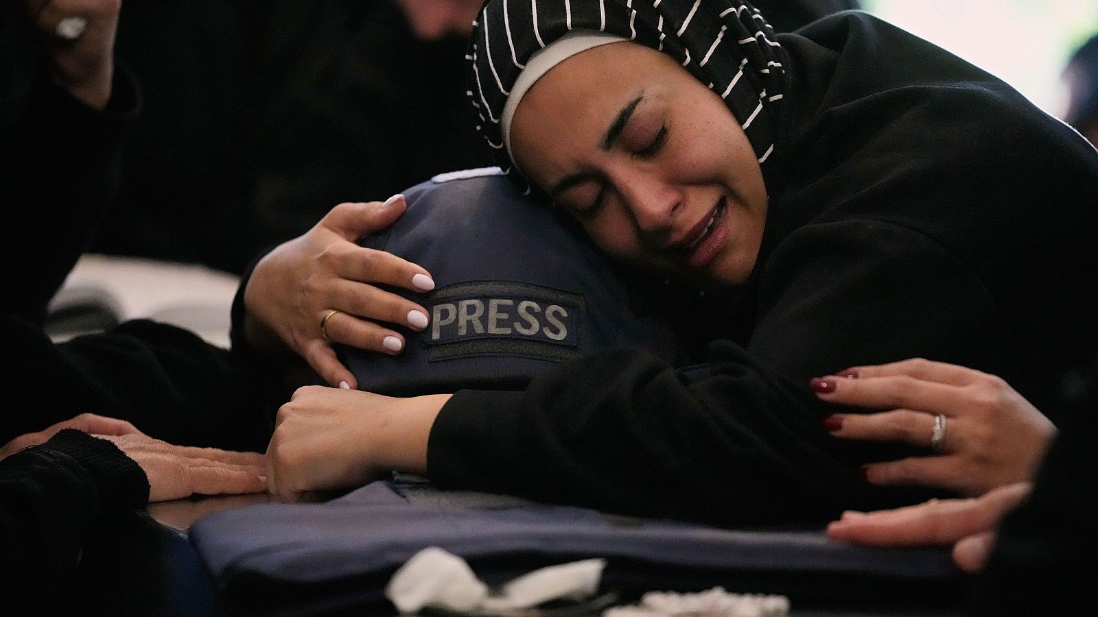 Zainab, hermana de la periodista libanesa Amal Khalil, quien murió el miércoles en un ataque aéreo israelí, abraza su casco mientras llora junto a su ataúd en la aldea de Baysariyeh, al sur del Líbano, el jueves 23 de abril de 2026.