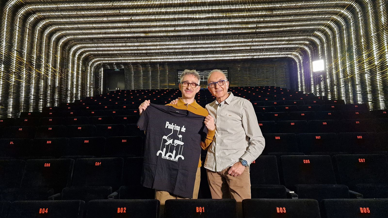 Alberto del Campo, padrino de 'Días de cine', y Gerardo Sánchez, director del programa, en un auditorio vacío. Alberto muestra una camiseta con el logo del programa.