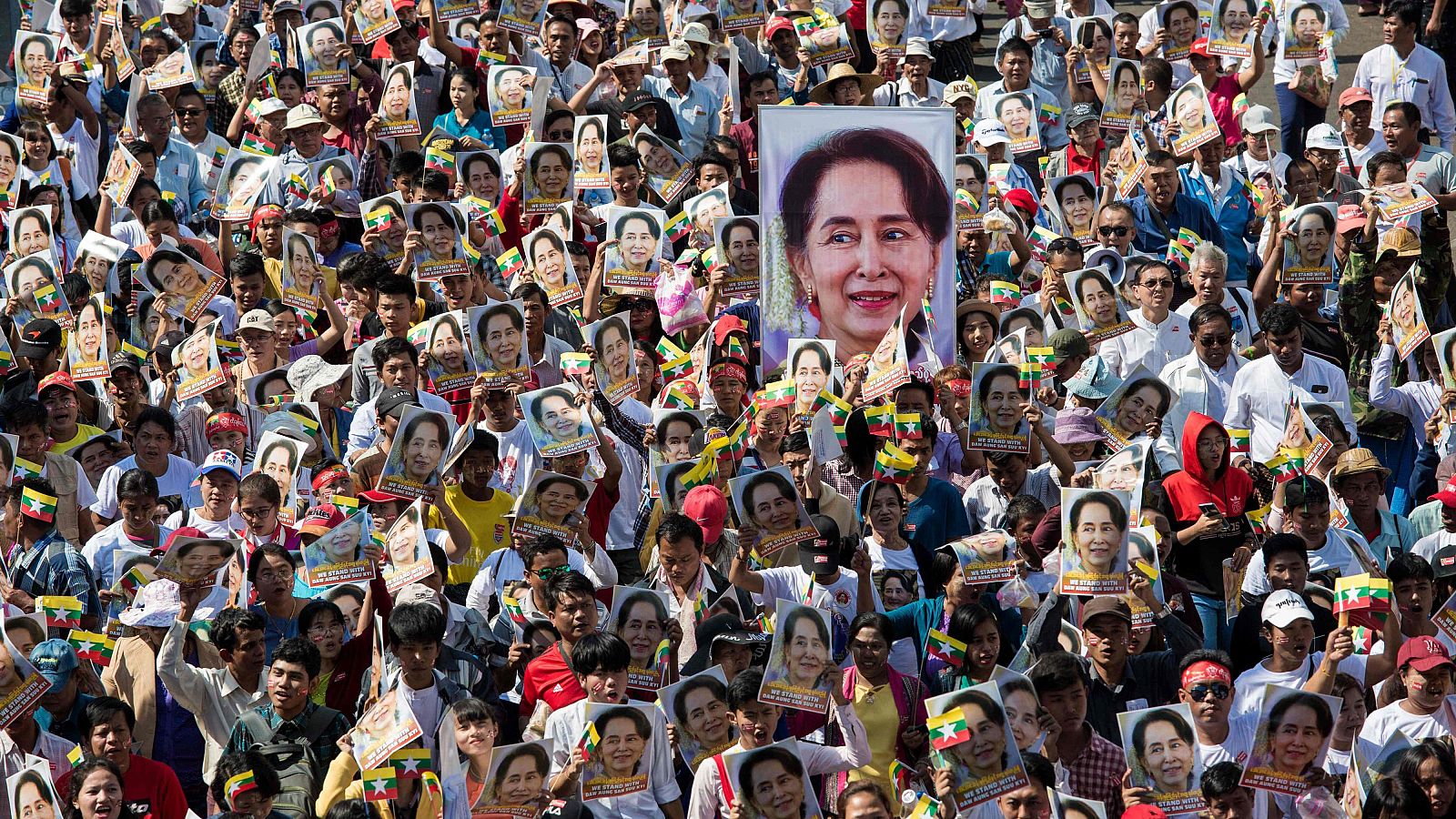 Multitudinaria manifestación de apoyo a Aung San Suu Kyi en Myanmar, con miles de personas portando sus retratos y banderas nacionales.