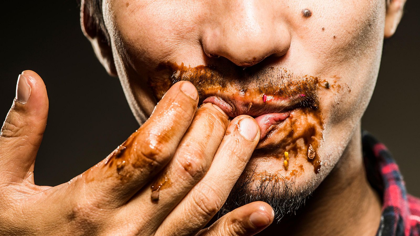 Fotografía en primer plano de un hombre de mediana edad lamiendo chocolate, primer plano