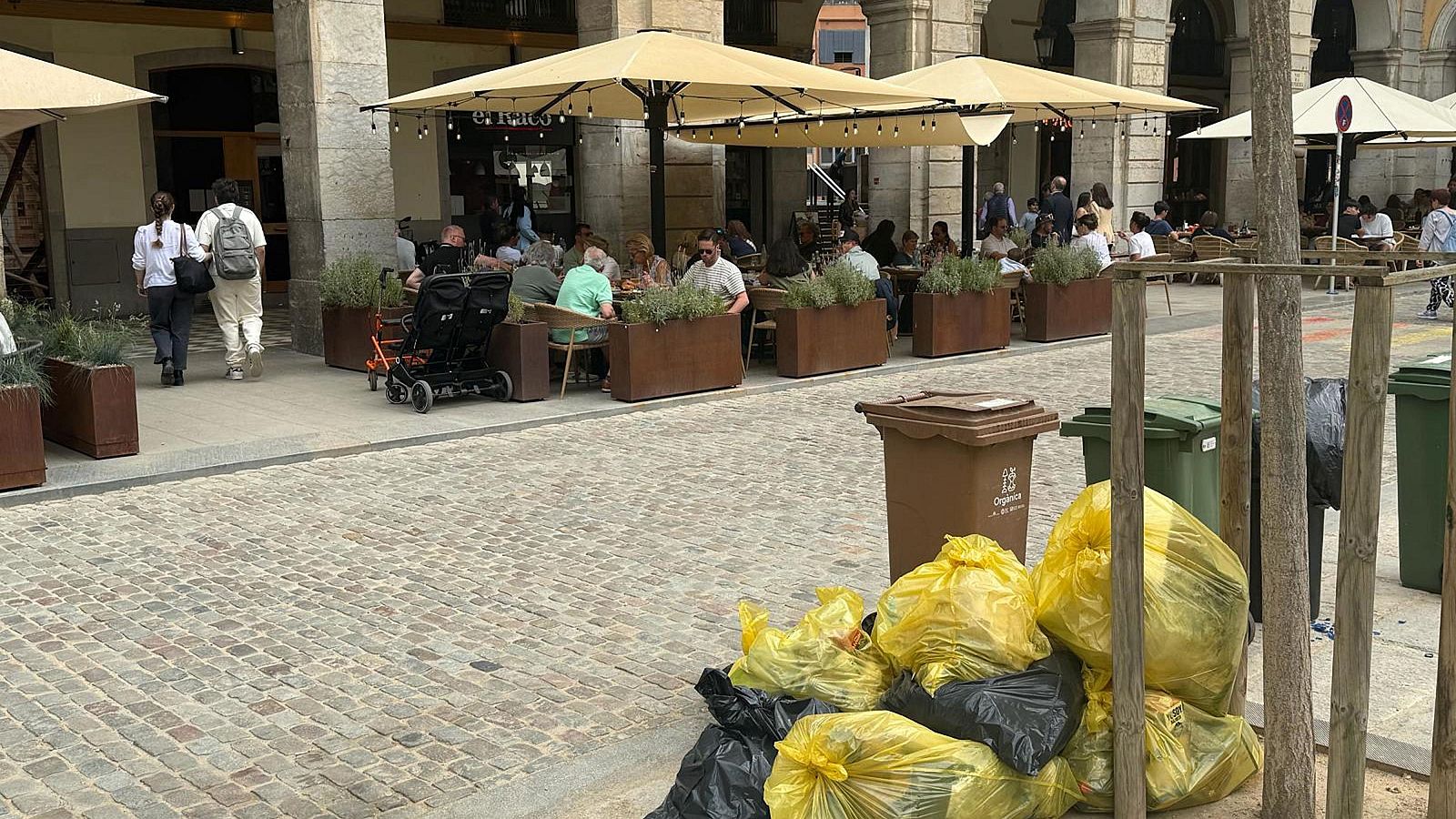 Persones dinant a la plaça Independència de Girona i brossa acumulada