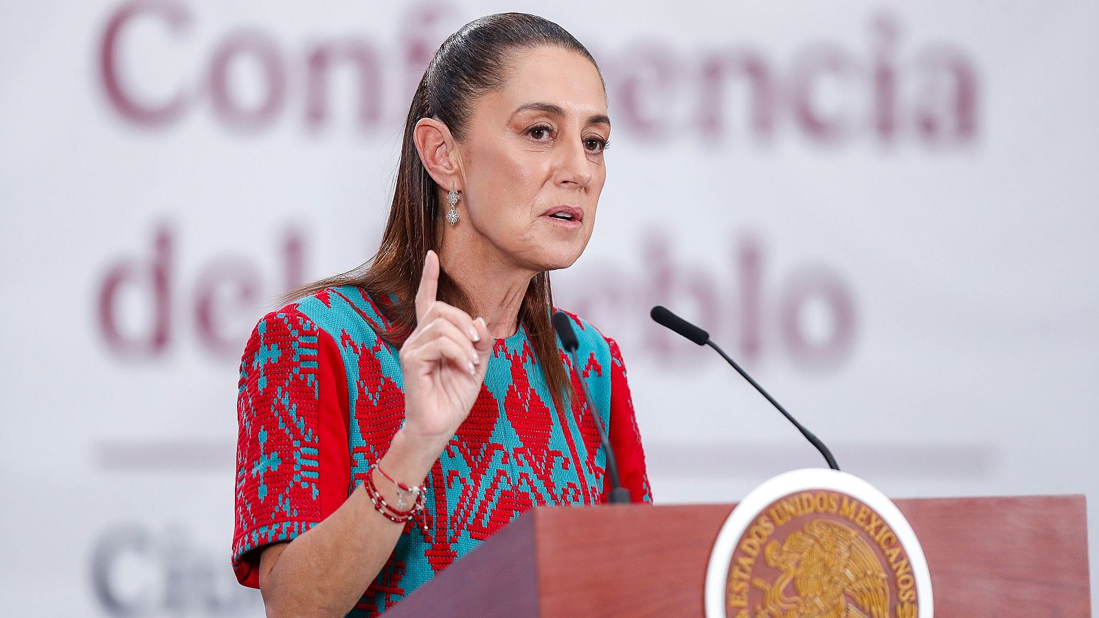 Claudia Sheinbaum, presidenta de México, en rueda de prensa en Palacio Nacional, con blusa geométrica y gesto enfático con la mano.