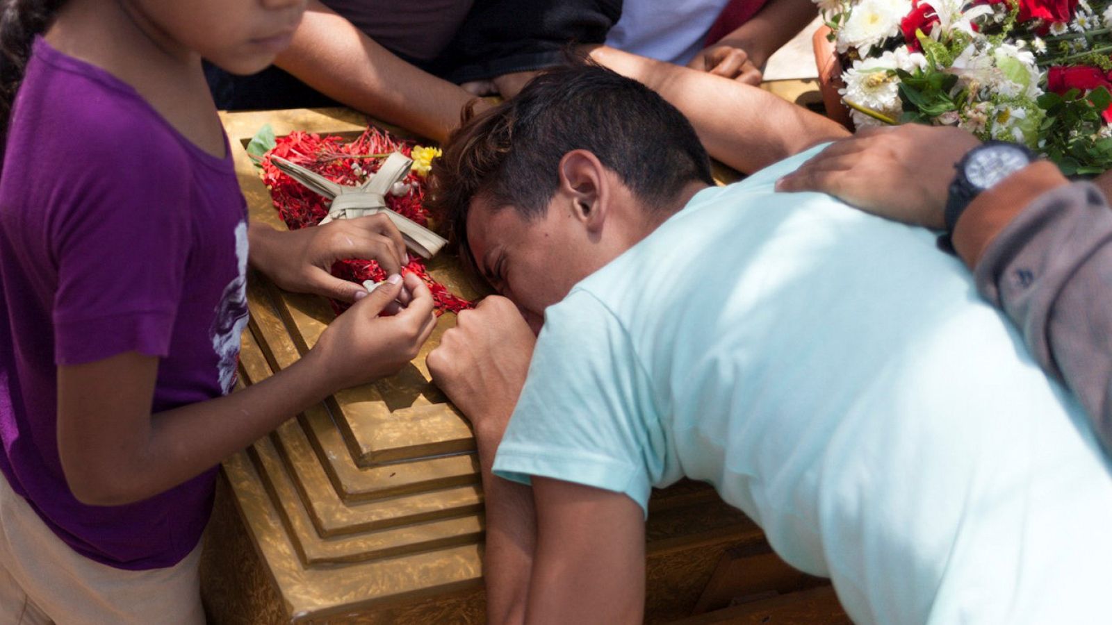 Un joven llora sobre el ataúd de una de las personas que falleció en el incendio de una comisaría.