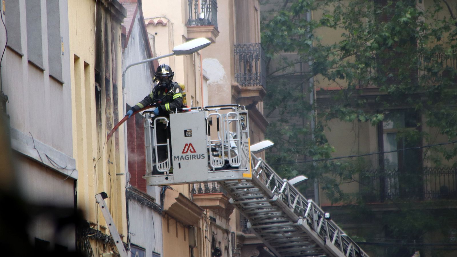 Els bombers remullen l'immoble calcinat per l'explosió d'una bombona de butà