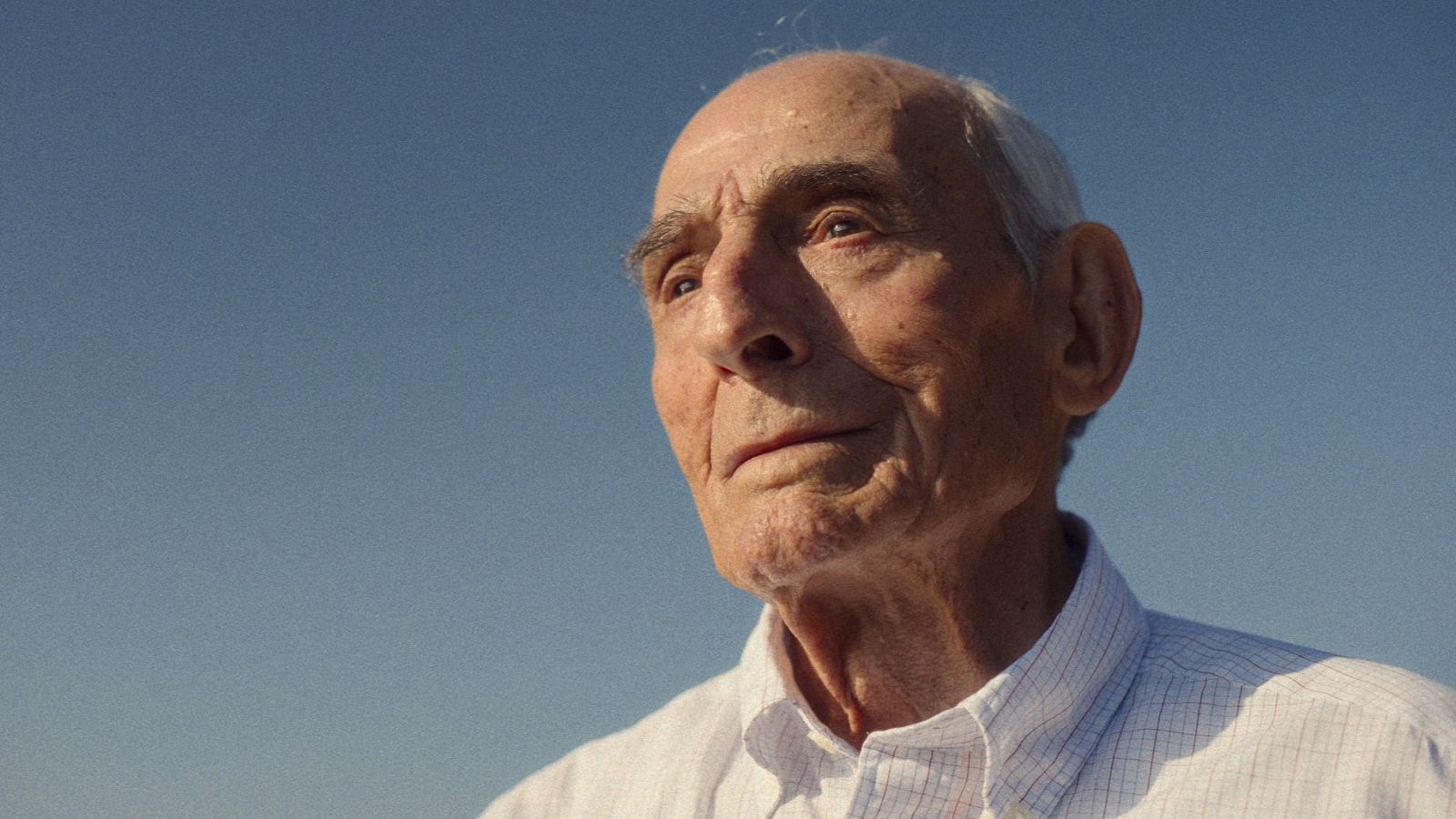 Retrato de Saturnino García, actor español de edad avanzada, con camisa de cuadros claros y fondo de cielo azul.