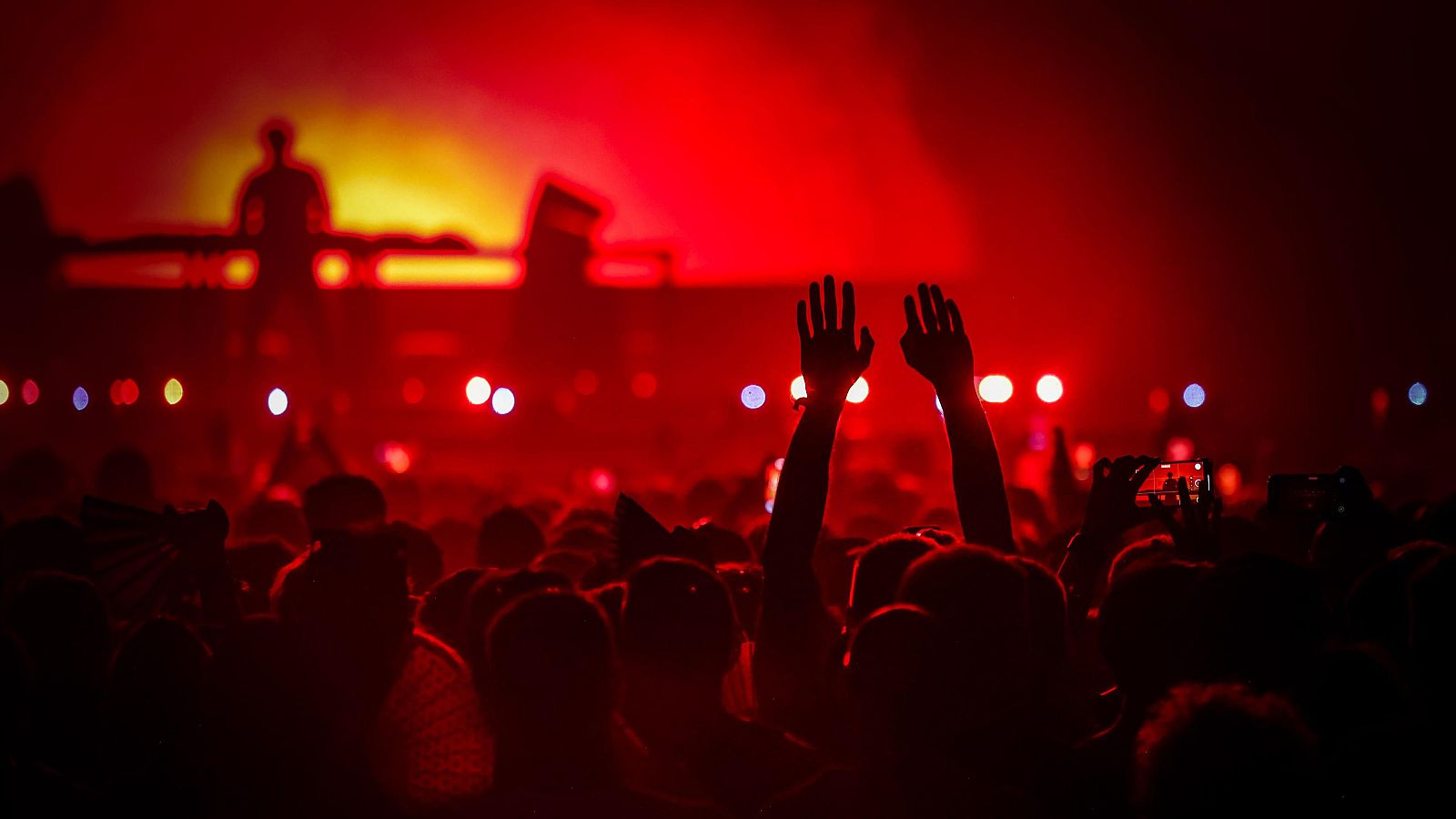 Eric Prydz actuando en el Sónar de Nit 2025, con luces rojas y una multitud animada. Se observa a alguien grabando con su móvil.