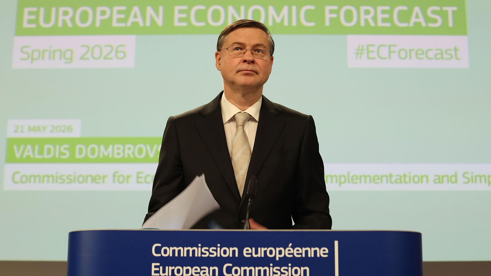 Valdis Dombrovskis, Comisario Europeo de Economía, presenta las previsiones económicas de primavera 2026, con el lema "EUROPEAN ECONOMIC FORECAST" y el hashtag "#ECForecast" visible.