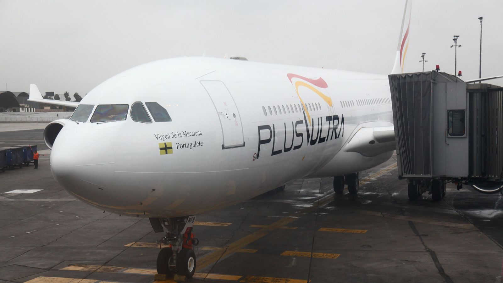 Avión blanco de "PLUS ULTRA" en pista con pasarela de embarque. Se lee "Virgen de la Macarena" y "Portugalete" en el fuselaje.