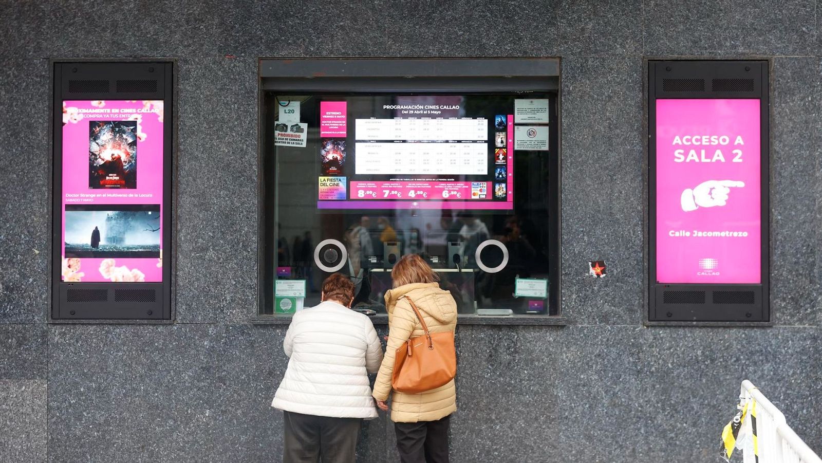 Personas mayores sacando entradas para una sala de cine durante el día.