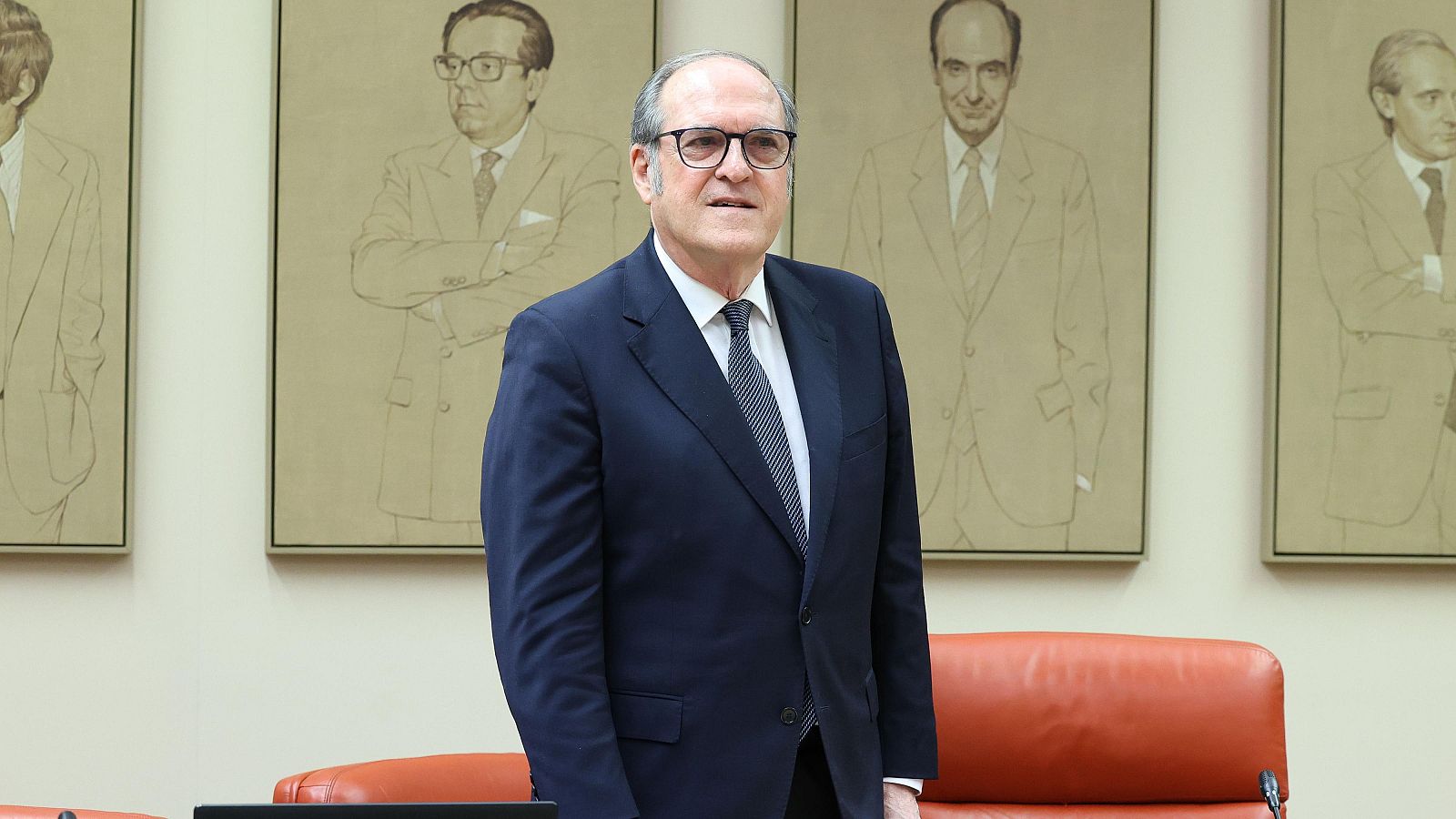 Ángel Gabilondo, Defensor del Pueblo, posa con traje azul y corbata de rayas. Al fondo, retratos enmarcados y un asiento de cuero naranja.