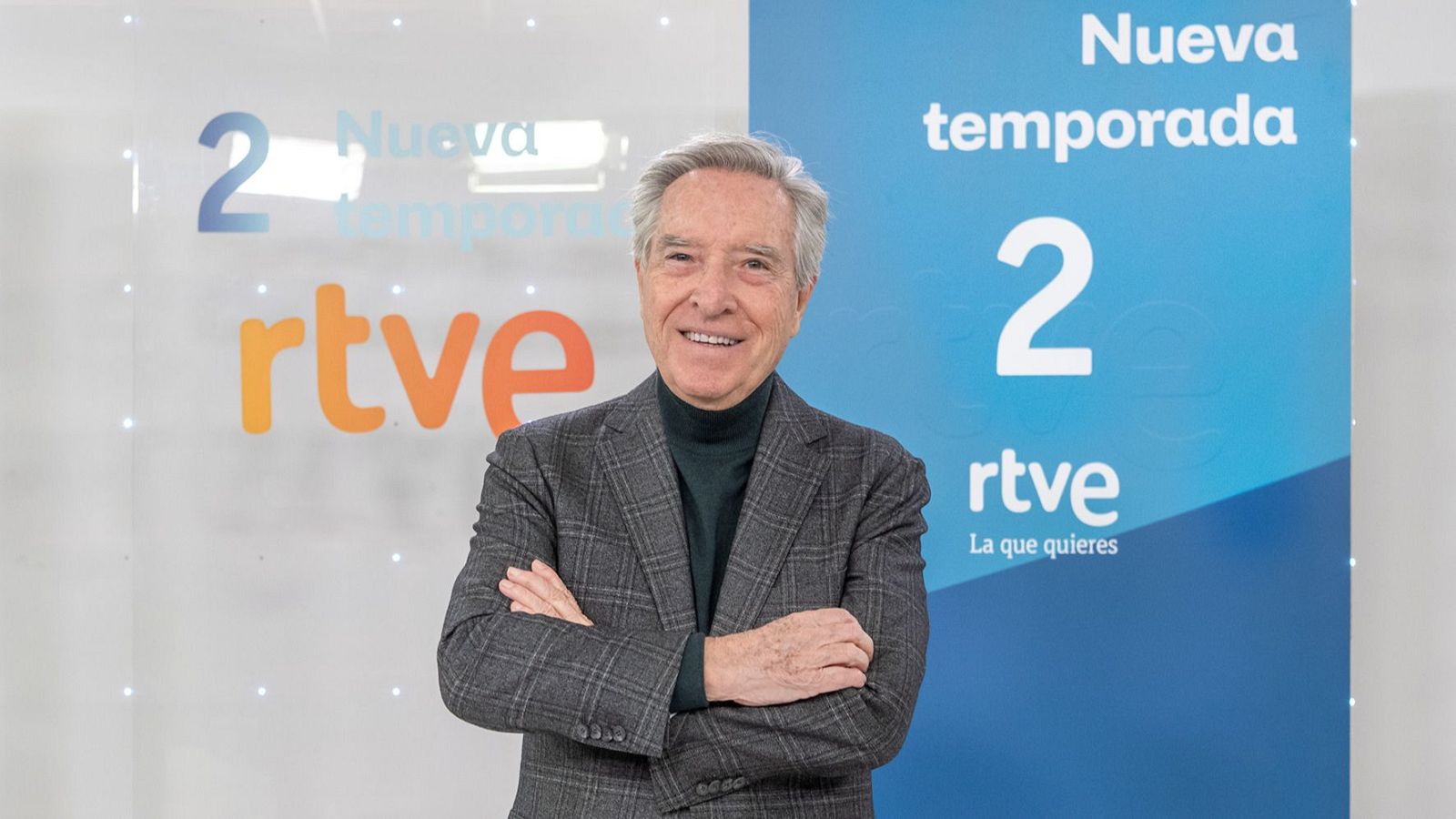 Iñaki Gabilondo sonríe a cámara con chaqueta de cuadros y jersey verde. Fondo dividido blanco y azul con "Nueva Temporada 2" y logo RTVE.