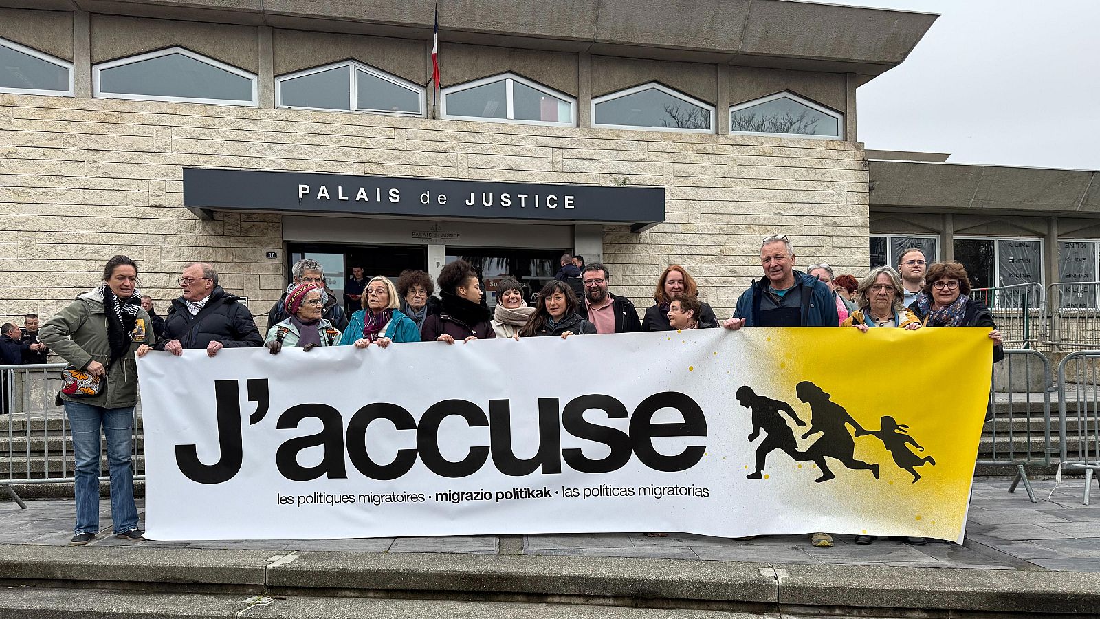 Los activistas juzgados por ayudar a migrantes durante la korrika de 2024 posan con una pancarta frente al Tribunal de Bayona