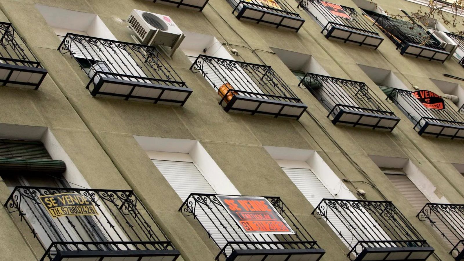 Edifici residencial verd oliva amb nombrosos balcons i cartells de "ES VEN". S'hi veuen telèfons: 678807428 i 91 311 2000.