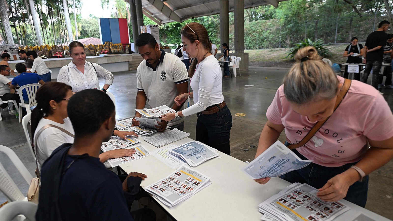Conteo de votos presidenciales 2022 en Cali, Colombia. Personas revisan papeletas y documentos electorales en un centro de votación.