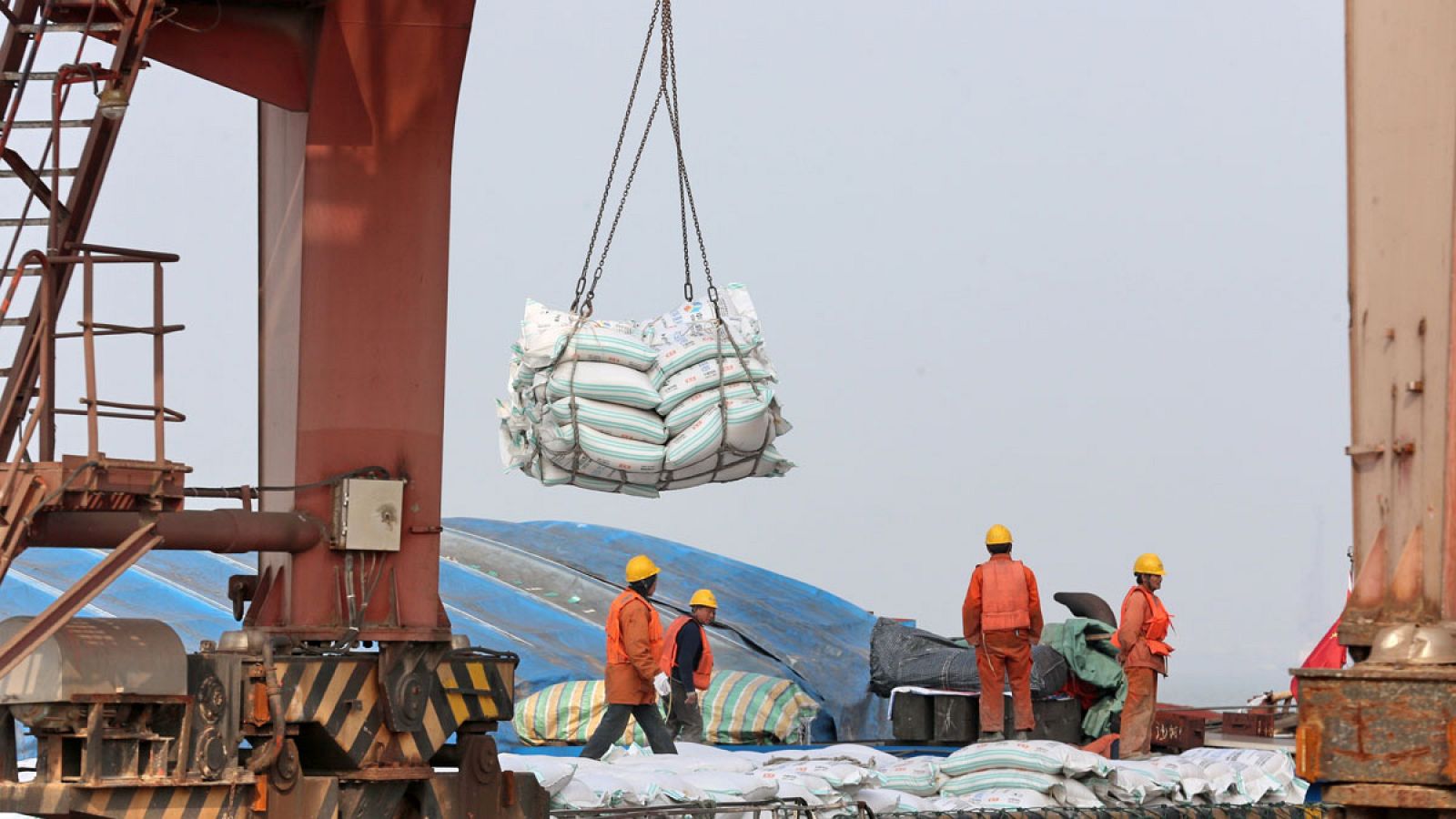 Operarios mientras transportan bolsas de habas de soja en un puerto en Nantong (China)
