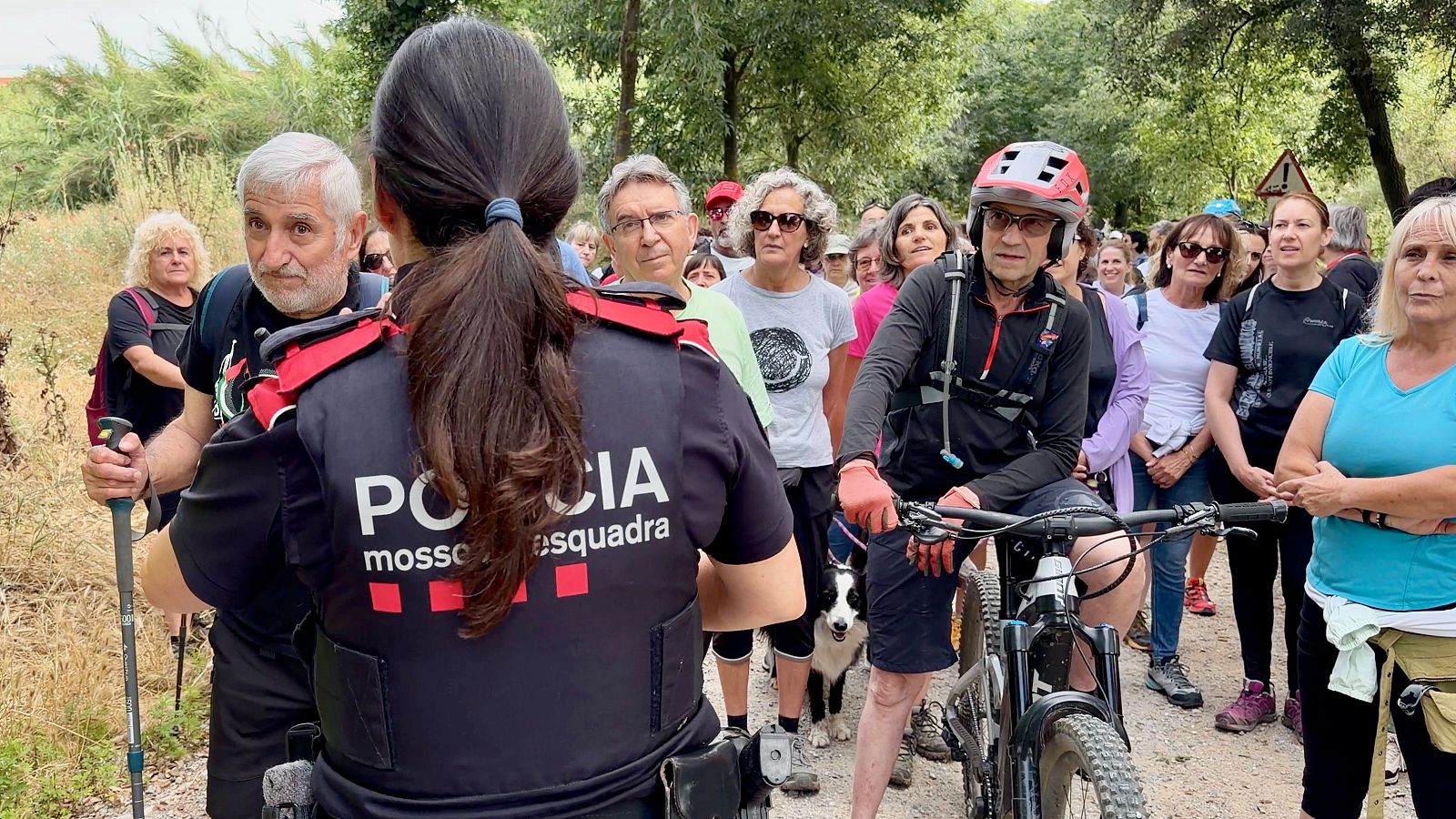 Una agent dels Mossos intenta indentificar els participants de la caminada reivindicativa per reclamar la reobertura de Collserola