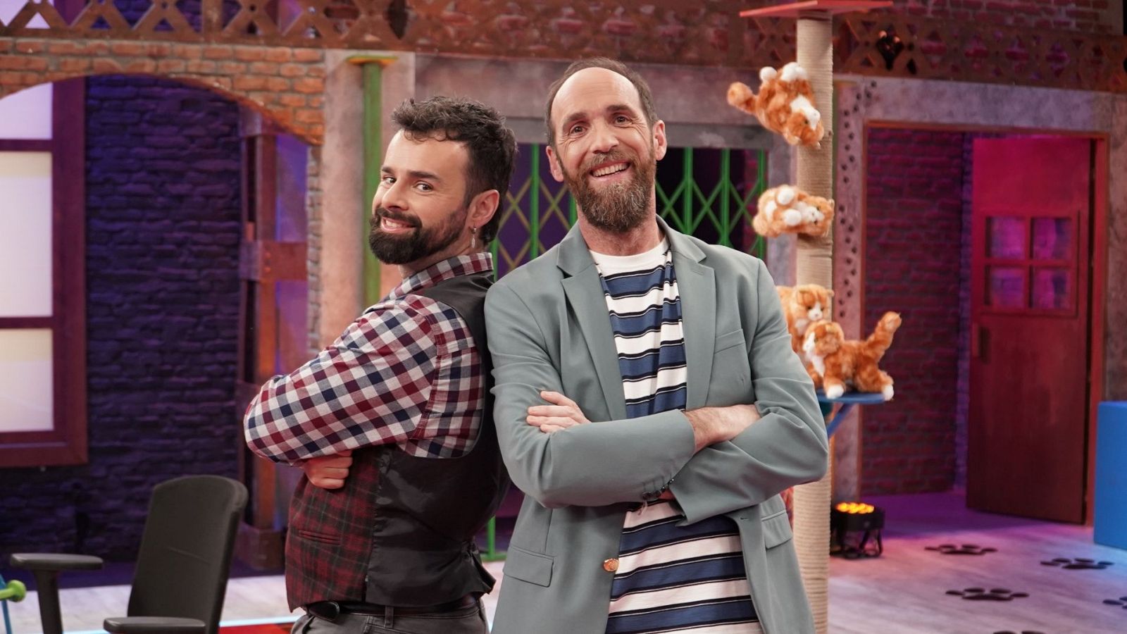 Ricardo Moure y Eduardo Sáenz de Cabezón, presentadores de "Órbita Laika", posan en el plató. Moure, a la izquierda, con camisa de cuadros y brazos cruzados a la espalda. Sáenz de Cabezón, a la derecha, con americana azul verdosa y brazos cruzados al pecho.