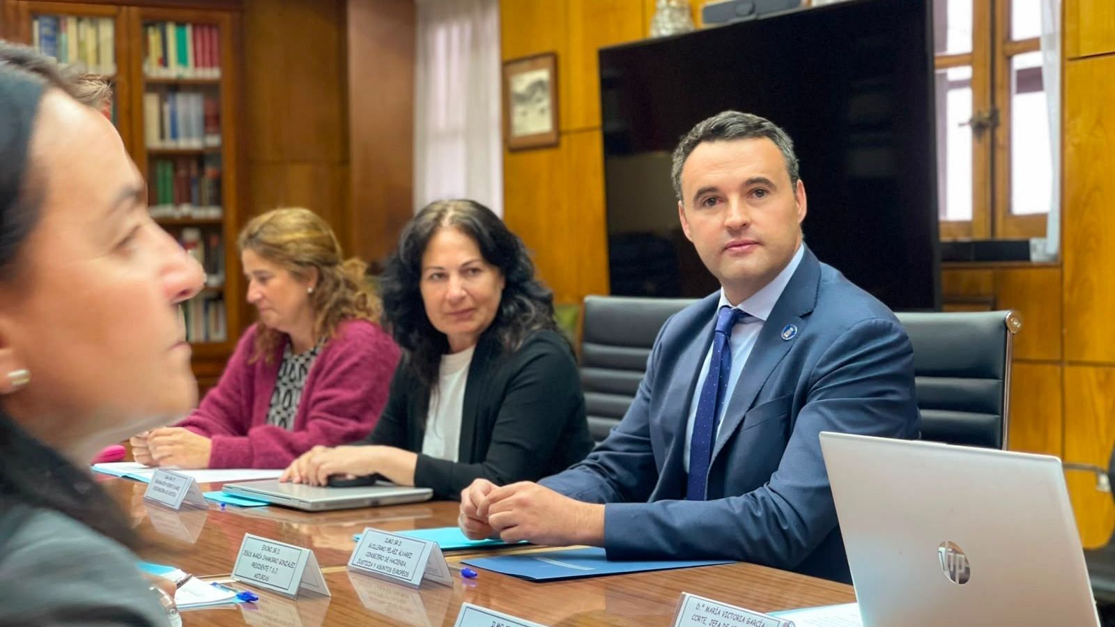 Guillermo Peláez, Consejero de Hacienda, preside una reunión formal junto a Alicia Cañas y María Jesús Álvarez. La mesa está dispuesta con portátiles, carpetas y documentos.