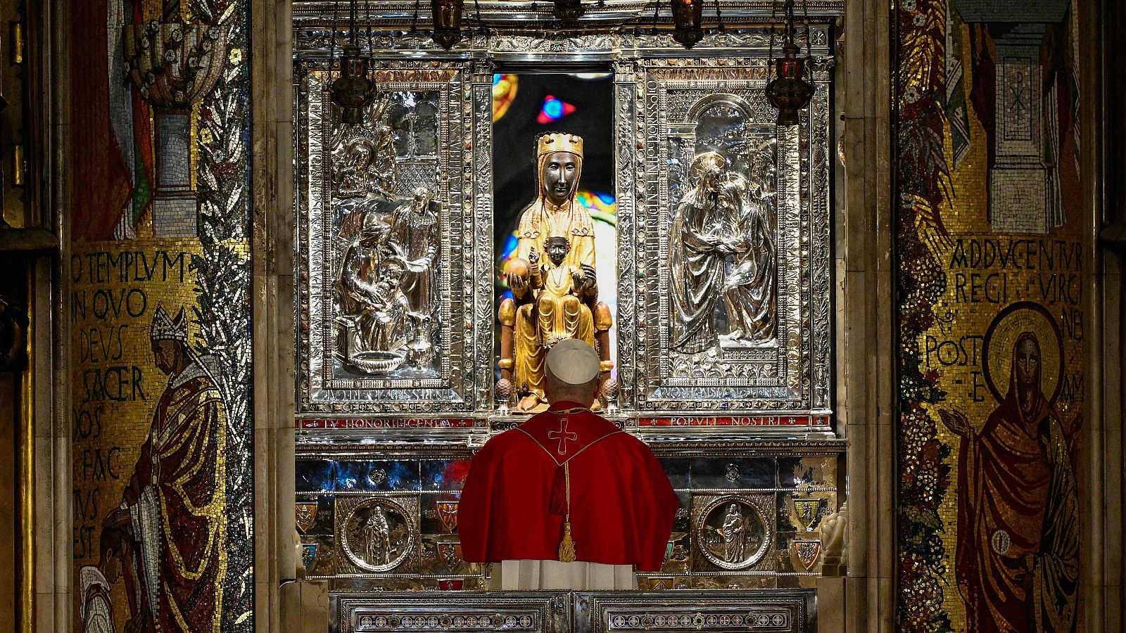Papa León XIV de espaldas, frente a la estatua de la Virgen de Montserrat "La Moreneta" en la Abadía de Montserrat. Detalle del retablo y mosaicos.