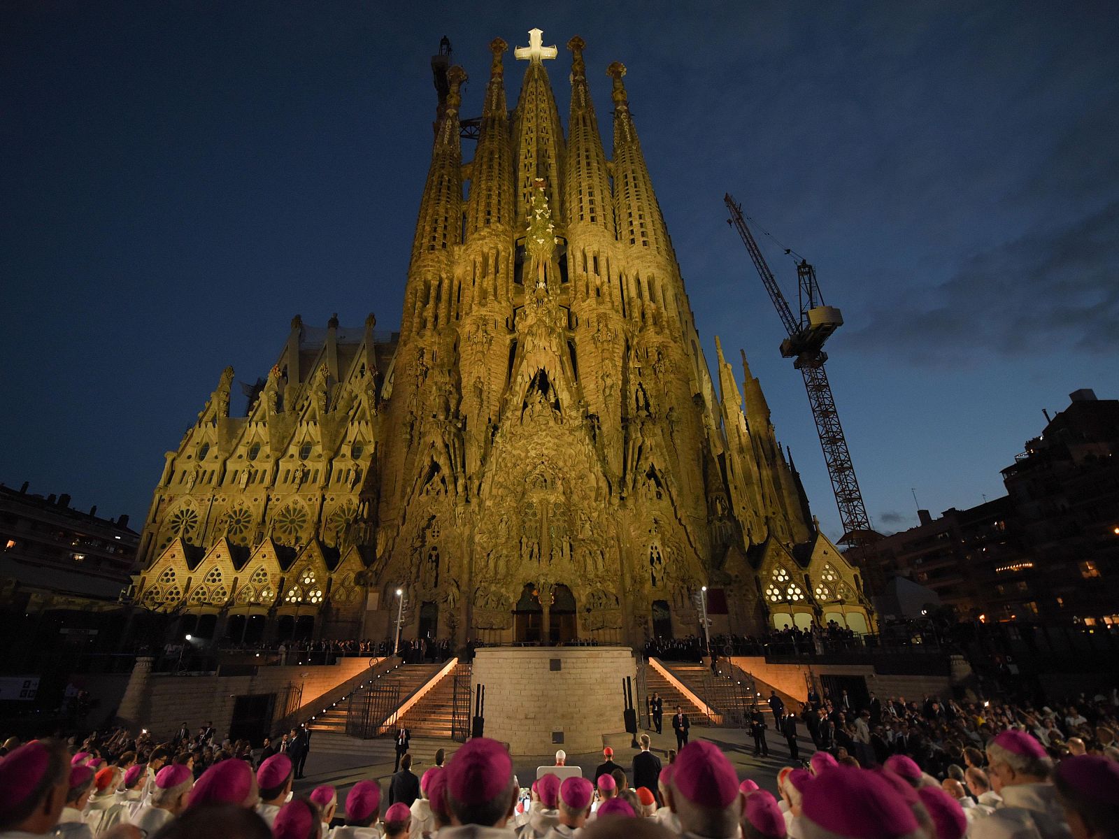 El Papa Lleó XIV, vestido con ornamentos papales blancos, bendice la Torre de Jesús de la Sagrada Familia, rodeado de obispos y cardenales, ante una multitud congregada.