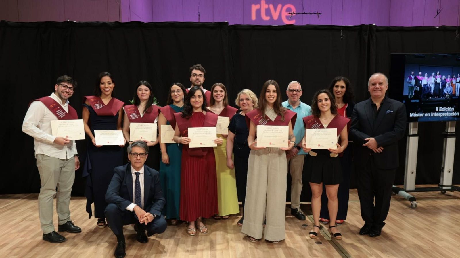 Clausura II Edición Máster en Interpretación RTVE. Graduados con estolas granates y diplomas posan con el Director del Instituto RTVE, Miguel Ángel García Cañamero, y el director de orquesta José Manuel Pérez Sierra.
