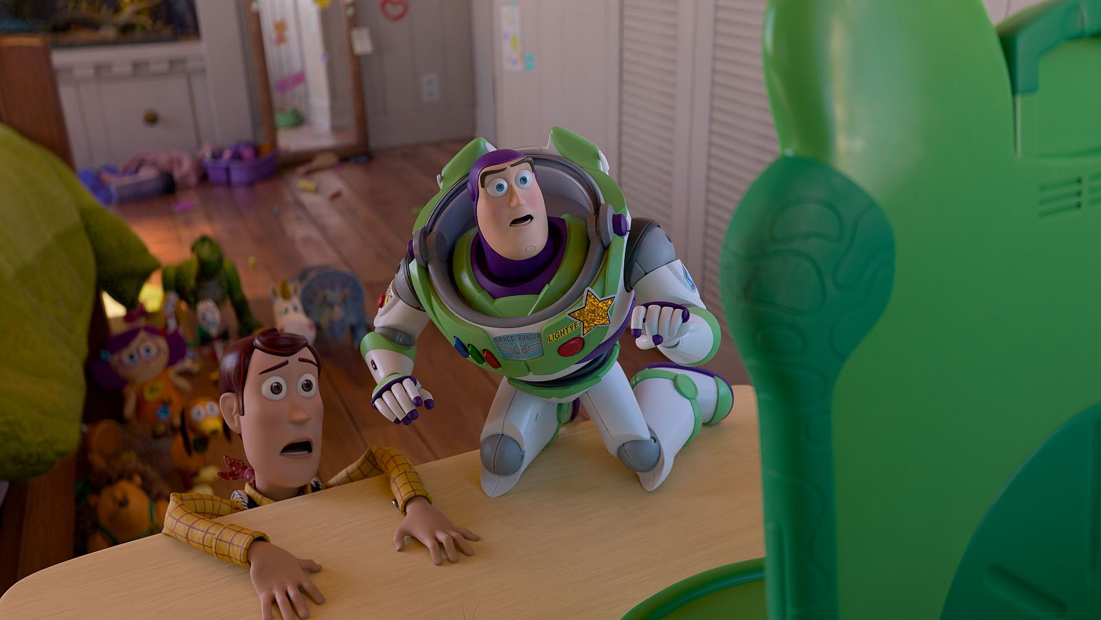 Woody y Buzz Lightyear, con ojos y bocas abiertas, muestran sorpresa en un fotograma de Toy Story 5. Se ven rodeados de juguetes en una habitación.