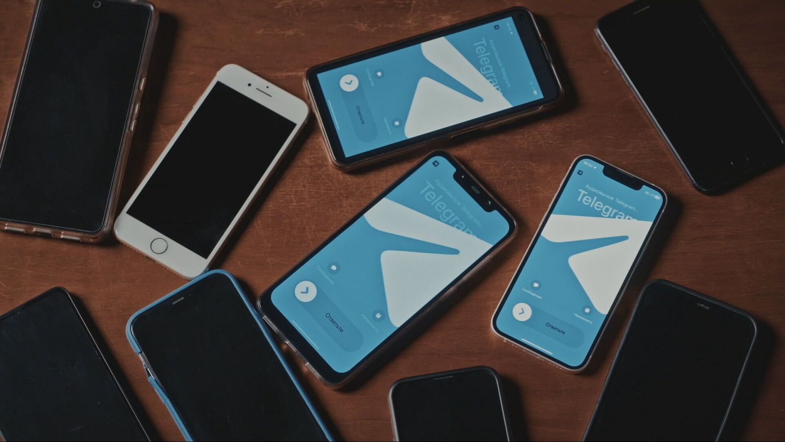 Ocho teléfonos móviles sobre madera, cuatro con la app Telegram visible en pantalla, mostrando logo y texto "Telegram".