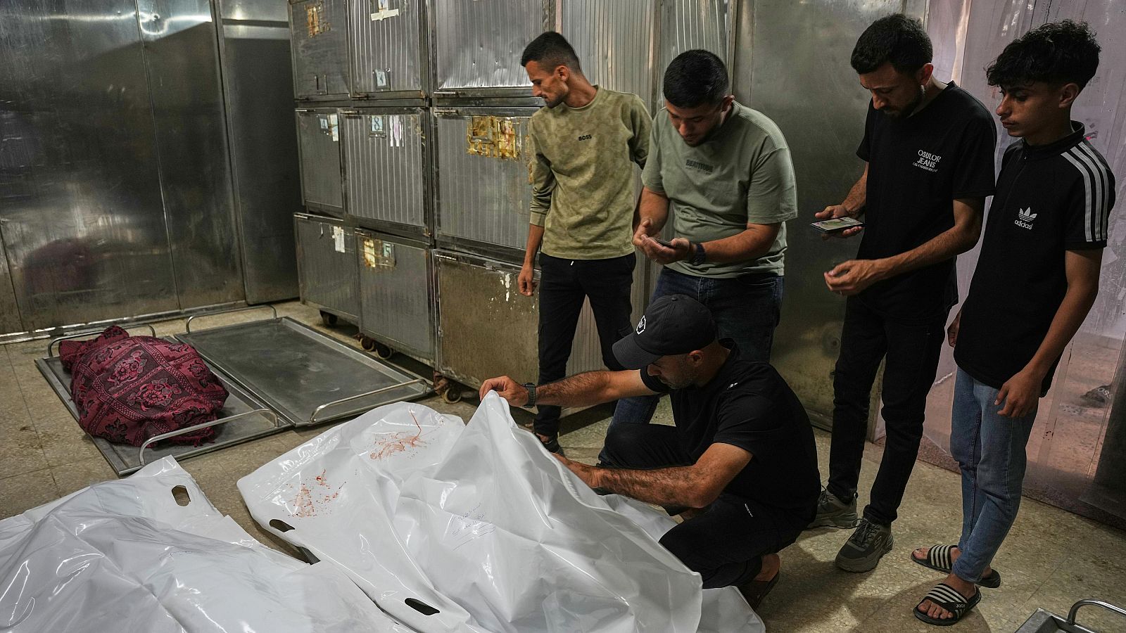 Un grupo de hombres contempla los cuerpos de dos jóvenes palestinas, Zeina y su hermana Lana asesinadas en un ataque aéreo israelí