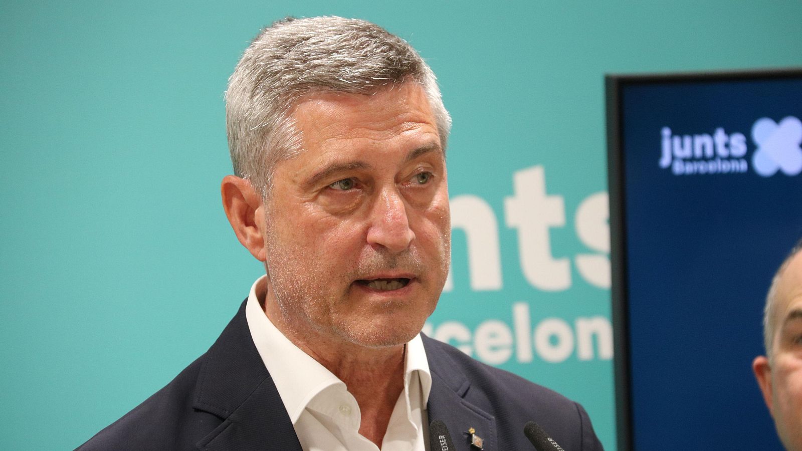 Primer pla de Jordi Martí, candidat de Junts per Barcelona, parlant en un esdeveniment polític. Es distingeixen elements del partit al fons.