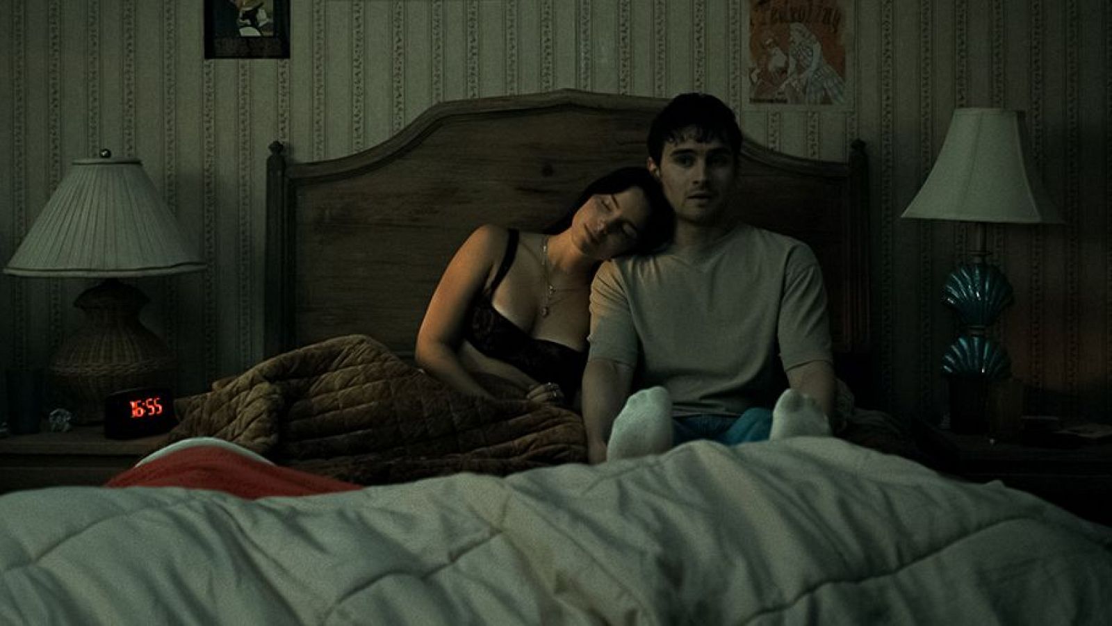 Fotograma de 'Obsession' con un hombre y una mujer en una cama. El reloj marca 16:55. Ambiente íntimo y de recogimiento.
