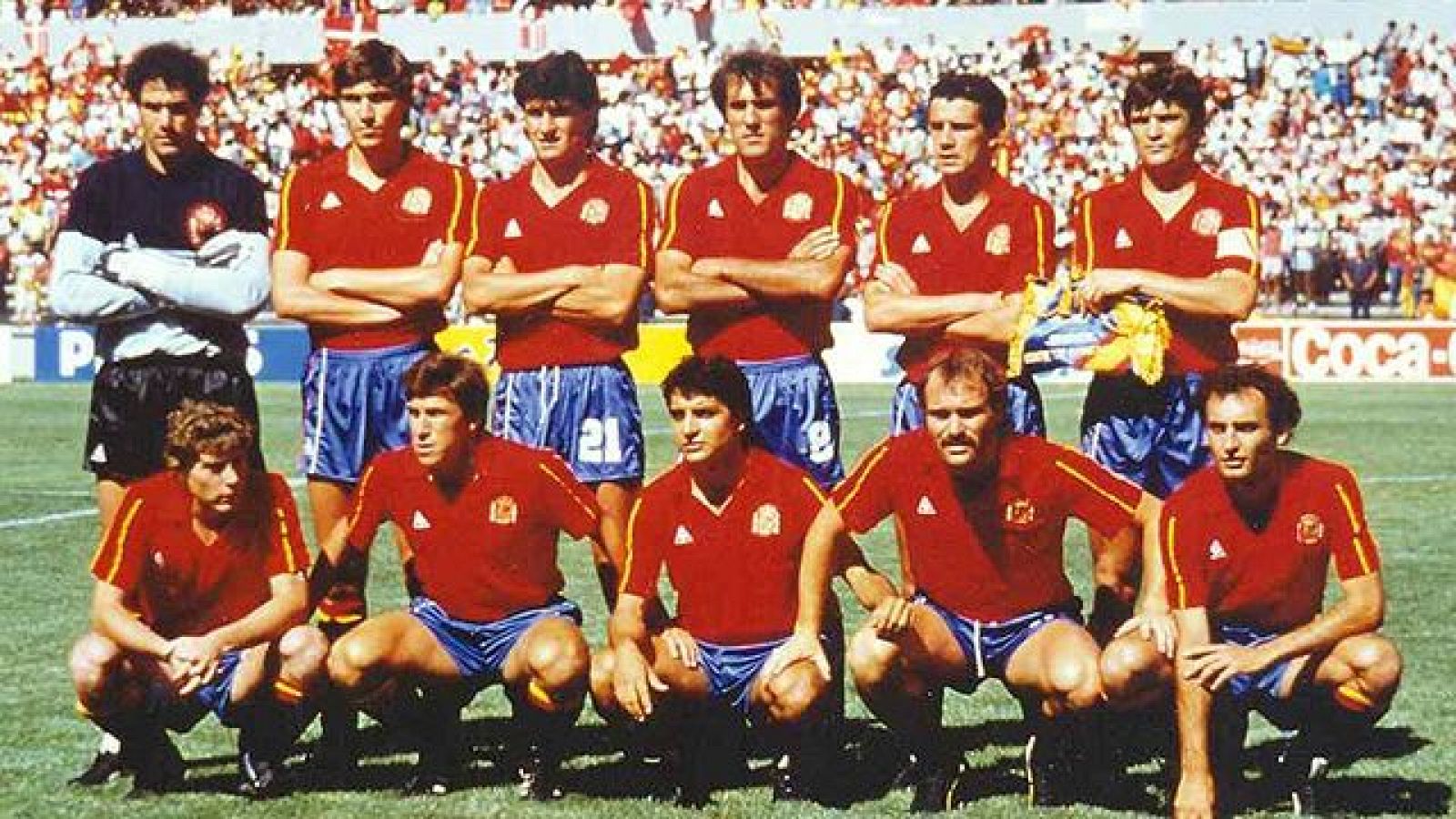 Once jugadores de la Selección Española posan en el campo del Mundial de México 1986. Equipación roja y azul, césped verde y público en las gradas.