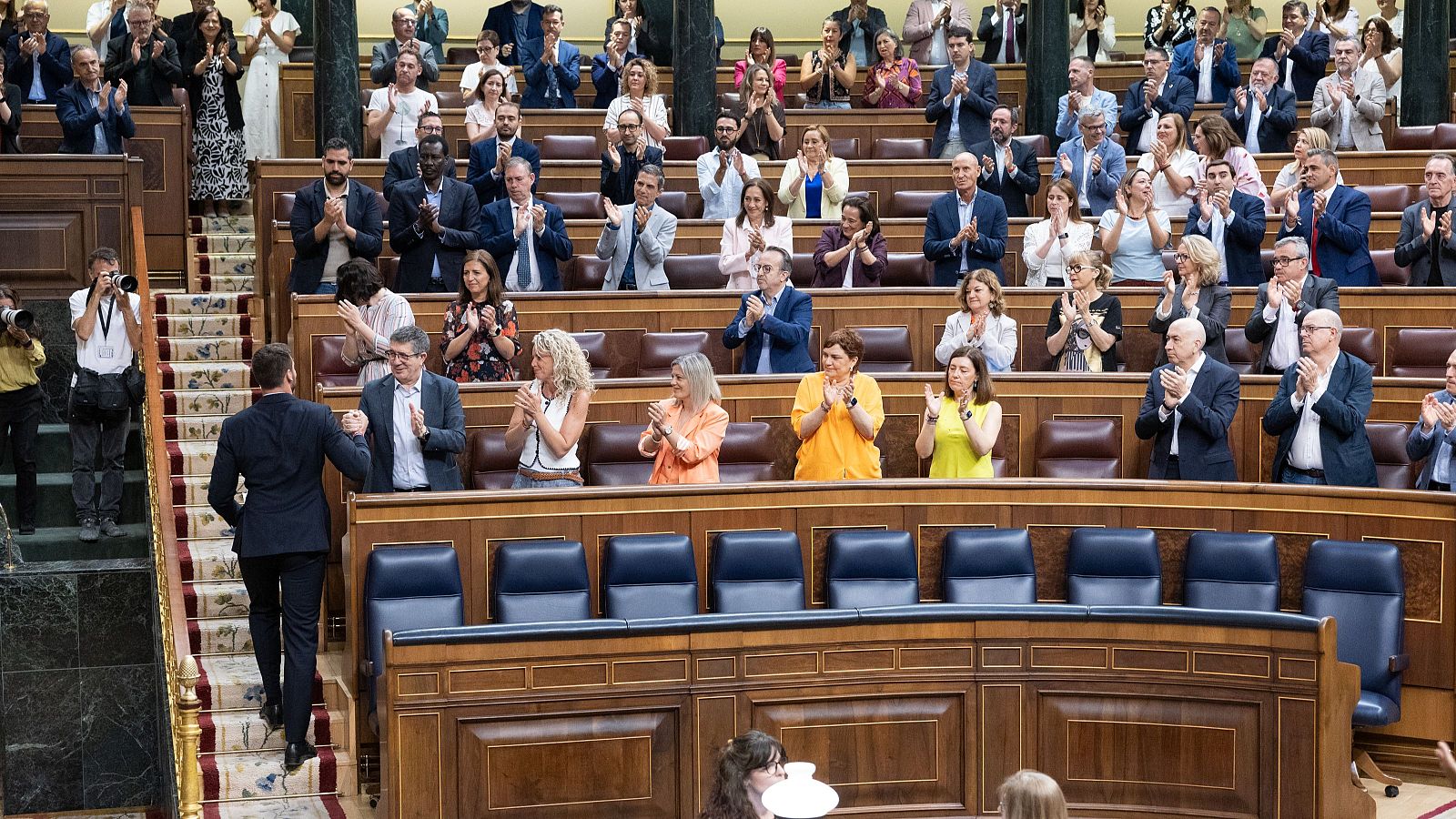Pedro Sánchez saluda a Patxi López en el Congreso de los Diputados, rodeados de diputados aplaudiendo en señal de aprobación.