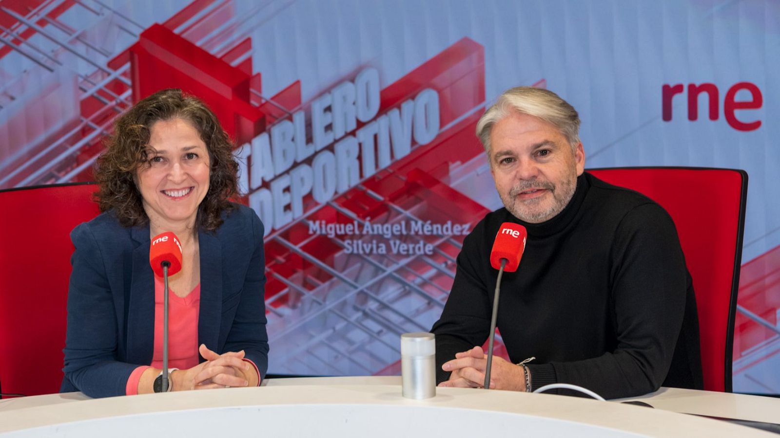 Silvia Verde y Miguel Ángel Méndez en un estudio de RNE, con micrófonos y la pantalla del programa "TABLERO DEPORTIVO" de fondo.