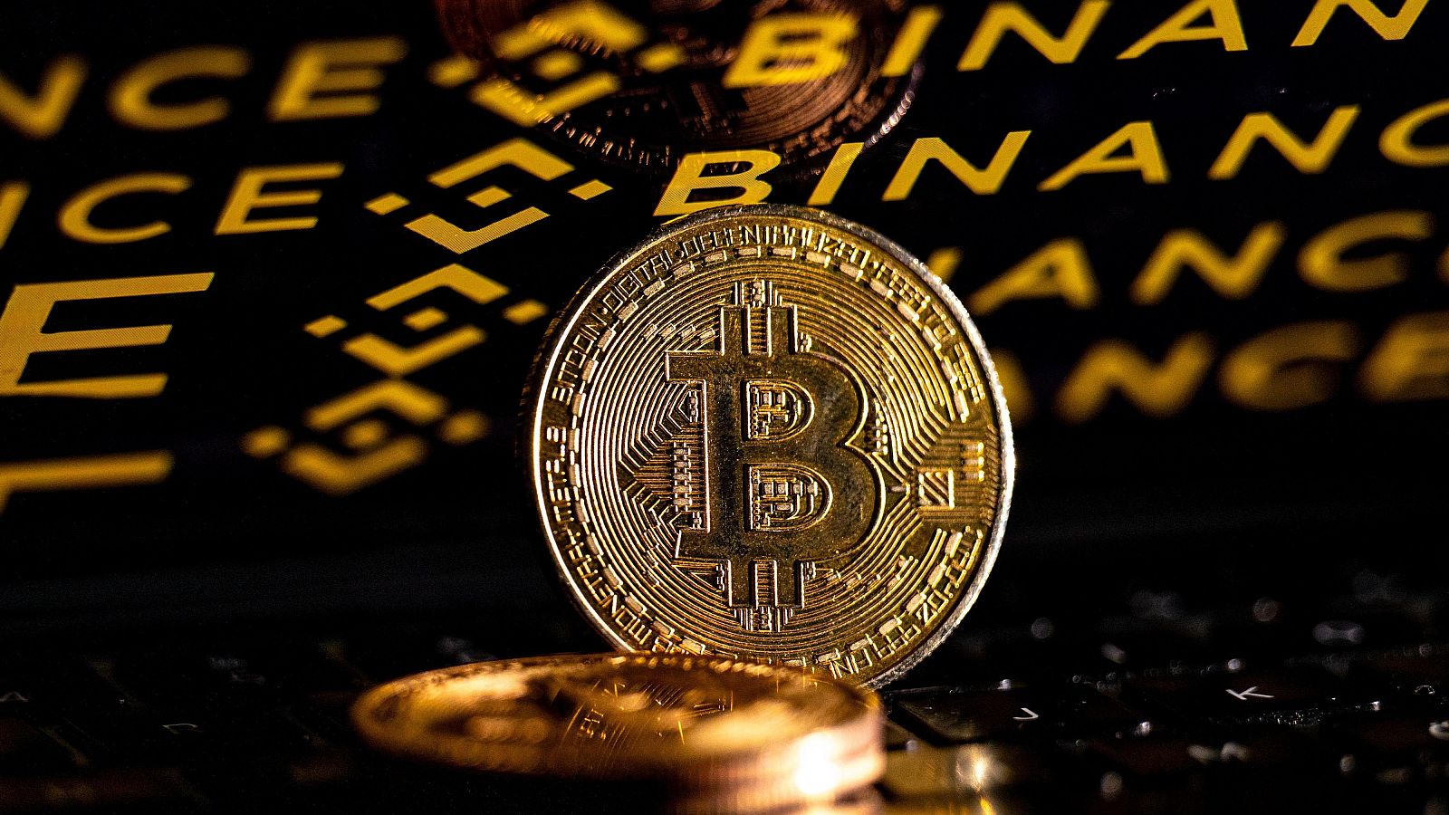 Moneda de Bitcoin dorada con texto "BITCOIN DIGITAL DECENTRALIZED PEER TO PEER" y fondo con "BINANCE".