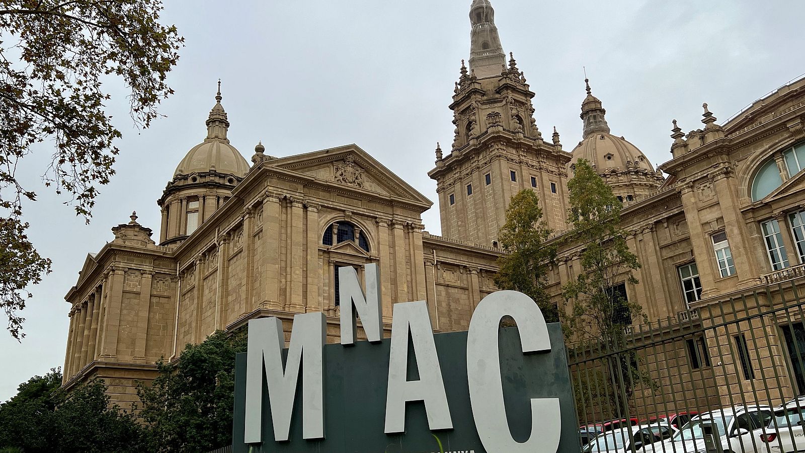 El Museu Nacional d'Art de Catalunya (MNAC) a Barcelona, amb el seu nom en grans lletres blanques davant de l'edifici monumental sota un cel ennuvolat.