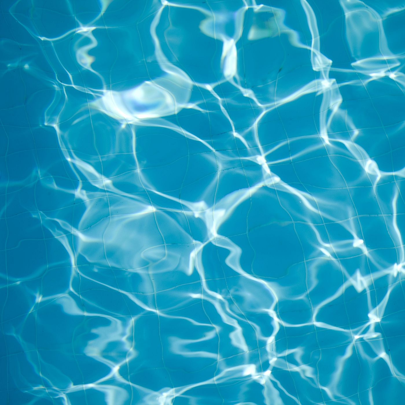 Agua de piscina azul turquesa con reflejos de luz blanca sobre un fondo de baldosas azules. Patrón dinámico y abstracto.