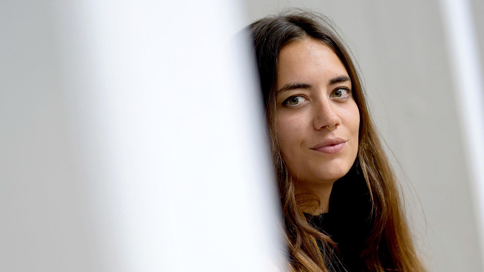 Primer plano de Gemma Blasco, con cabello castaño, ojos claros y sonrisa sutil. Lleva un piercing septum. Fondo claro y desenfocado.