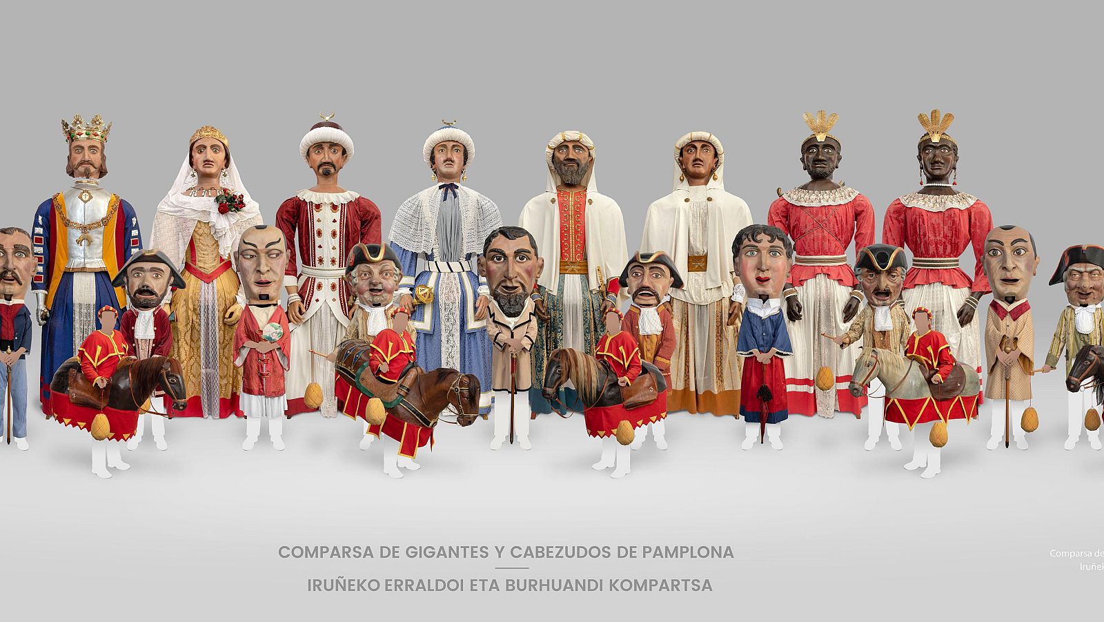 Detallada exhibición de la Comparsa de Gigantes y Cabezudos de Pamplona, con figuras representativas de distintas razas y el texto identificativo en español y euskera.