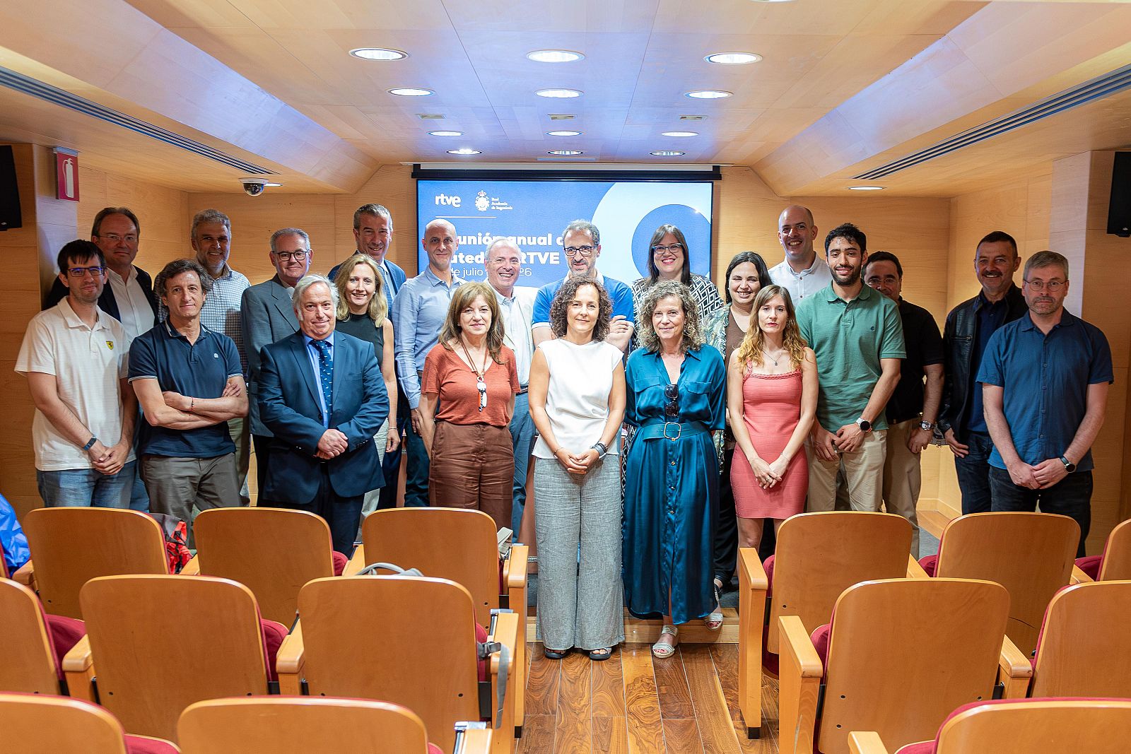 Grupo de 29 personas en la reunión anual de Cátedras RTVE 2023, con José Manuel Pérez Tornero en la primera fila. Pantalla de RTVE al fondo.