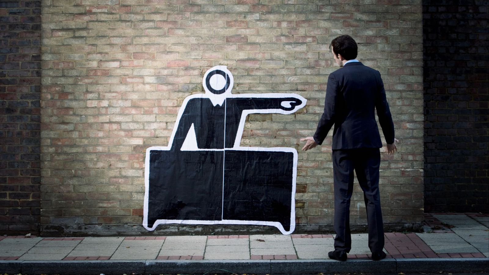 Un hombre observa una pintura en la pared que indica alguien despidiéndole