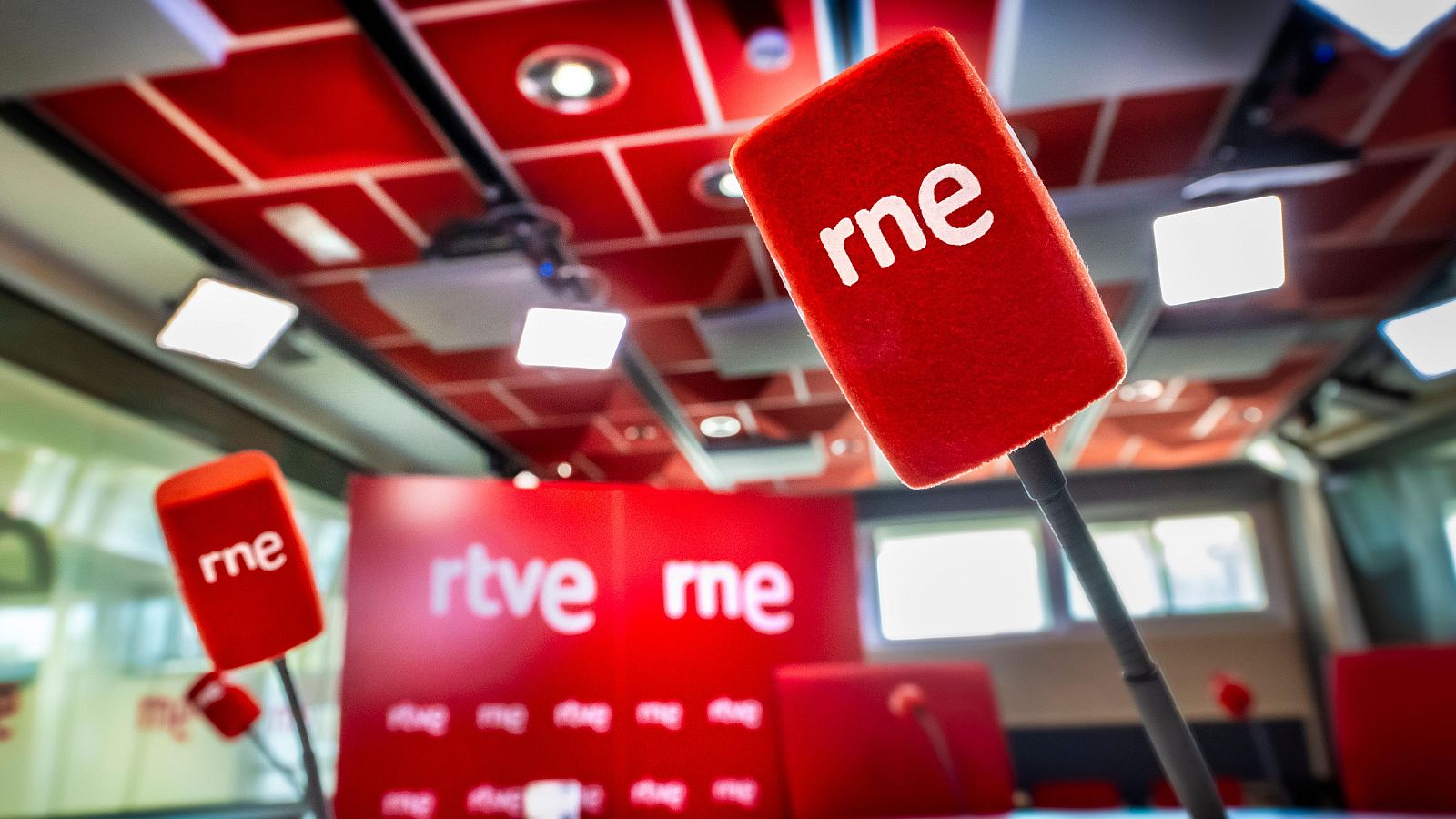 Estudio de RNE con micrófonos y logos "rne" y "rtve" en rojo y blanco. Sin personas.