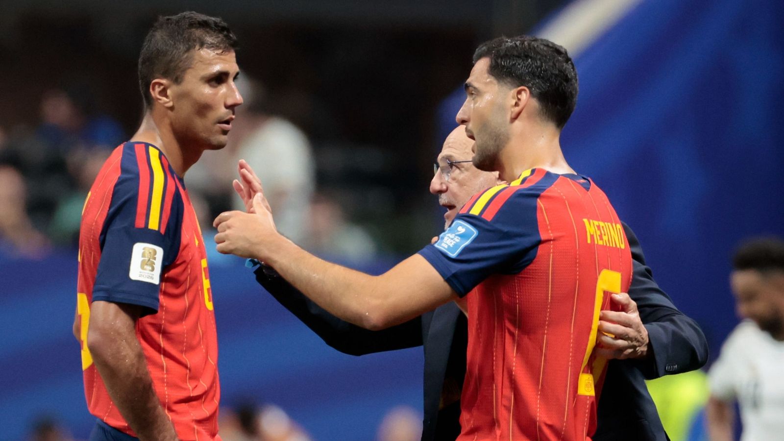 Luis de la Fuente da instrucciones a Rodri y Merino, ambos con la equipación de la selección española y el parche de la FIFA World Cup Qatar 2022.