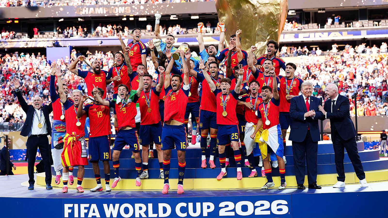 Jugadores de la selección española celebran la Copa del Mundo FIFA 2026 con el trofeo dorado, medallas y confeti. Trump, Infantino y Rubiales presentes. "CHAMPIONS" y "FINAL" en las gradas.