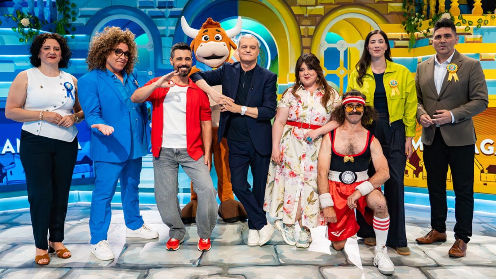 Presentadores, autoridades y padrinos de "El Grand Prix del Verano 2026" posan en un plató con decorado de fantasía. Se identifican Ramón García, Cristinini, Wilbur, Michelle Calvó, María Gómez, El Comodín y la mascota Nico.