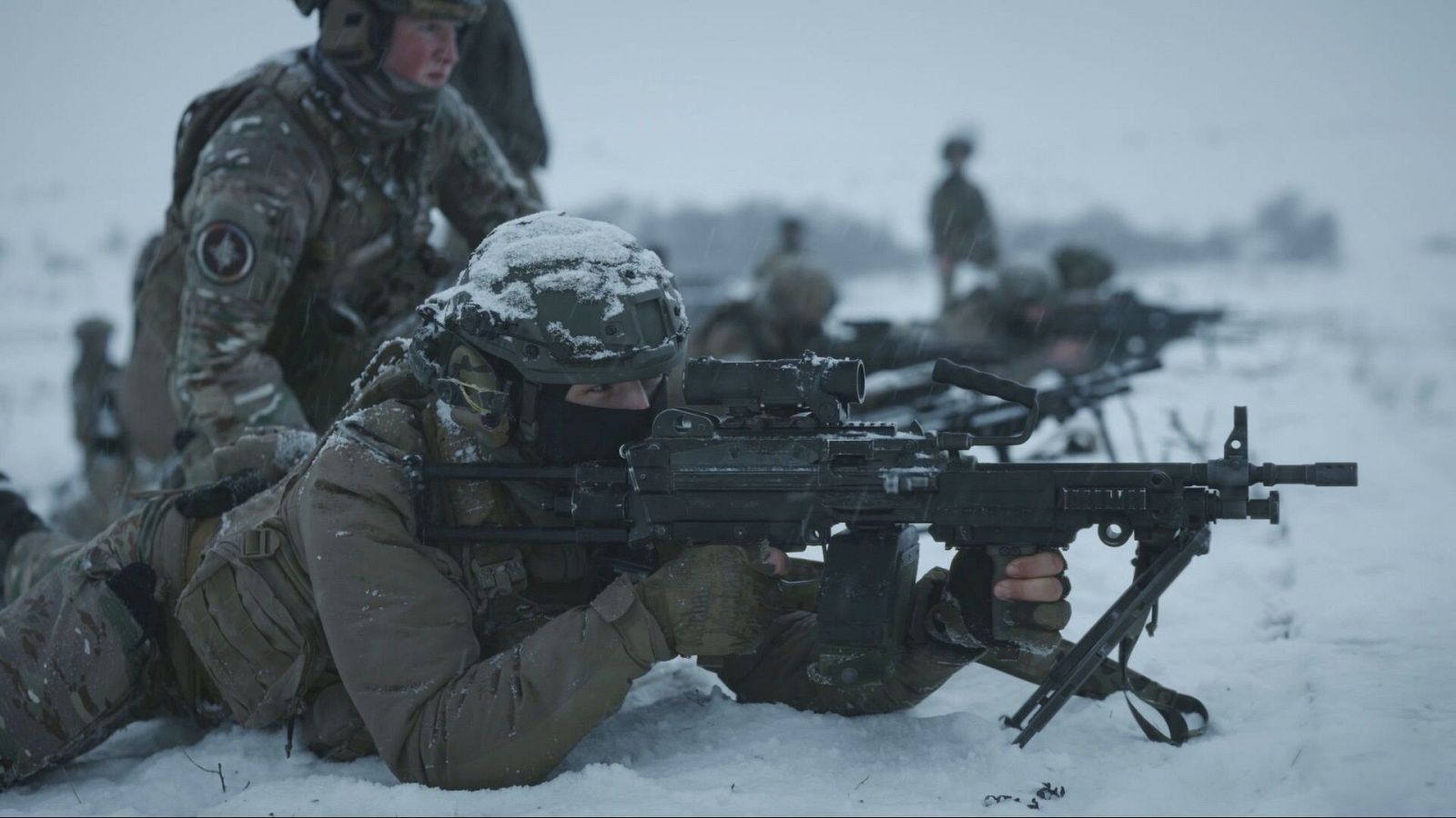 Soldado en posición de tiro prono con ametralladora ligera en un entorno nevado, durante un ejercicio militar invernal.