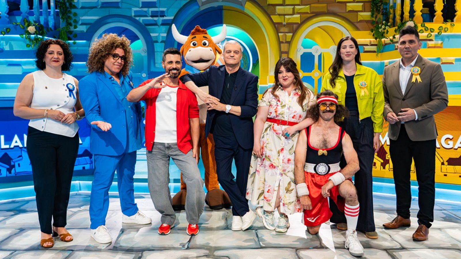 El equipo de "Grand Prix del Verano" posa en el plató con la mascota "La Vaquilla". Ramón García, Florentino Fernández, Miguel Lago, Michelle Calvó, Cristinini y Wilbur son visibles.