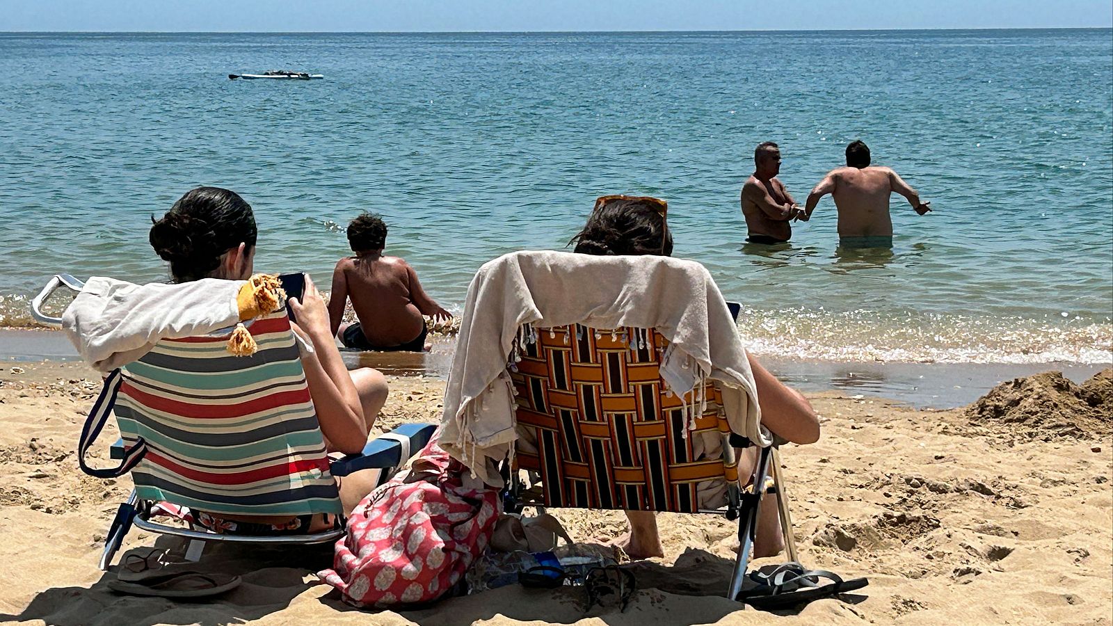 Dos mujeres toman el sol en primera línea de la playa de La Antilla, en Lepe (Huelva).