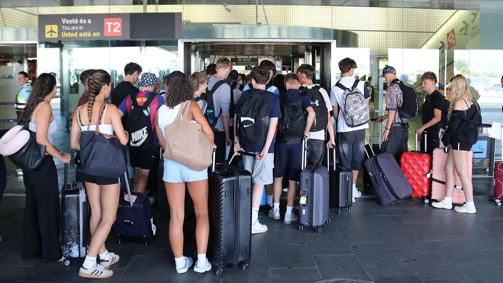 Desenes de passatgers fan cua per accedir a la terminal 2 de l'Aeroport del Prat